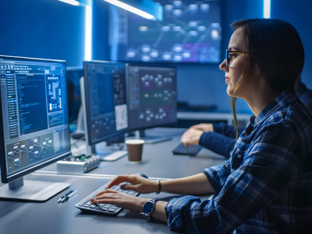 Smart Young Female IT Programer Working on Desktop Green Mock-up Screen Computer in Data Center System Control Room. Team of Young Professionals Programming Sophisticated Code